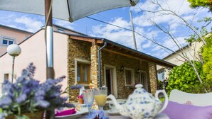 A table set outdoors with a teapot, a glass of juice, and a plate of food. - Casa Brais (Barreiros)