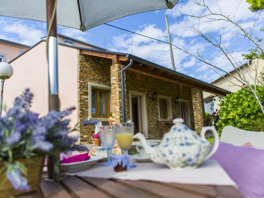 A table set outdoors with a teapot, a glass of juice, and a plate of food.