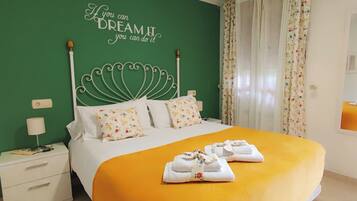 A neatly made bed with floral pillows, a green wall with a motivational quote, and a yellow bedspread.