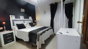 Un dormitorio con cama, mesitas de noche, escritorio y armario.