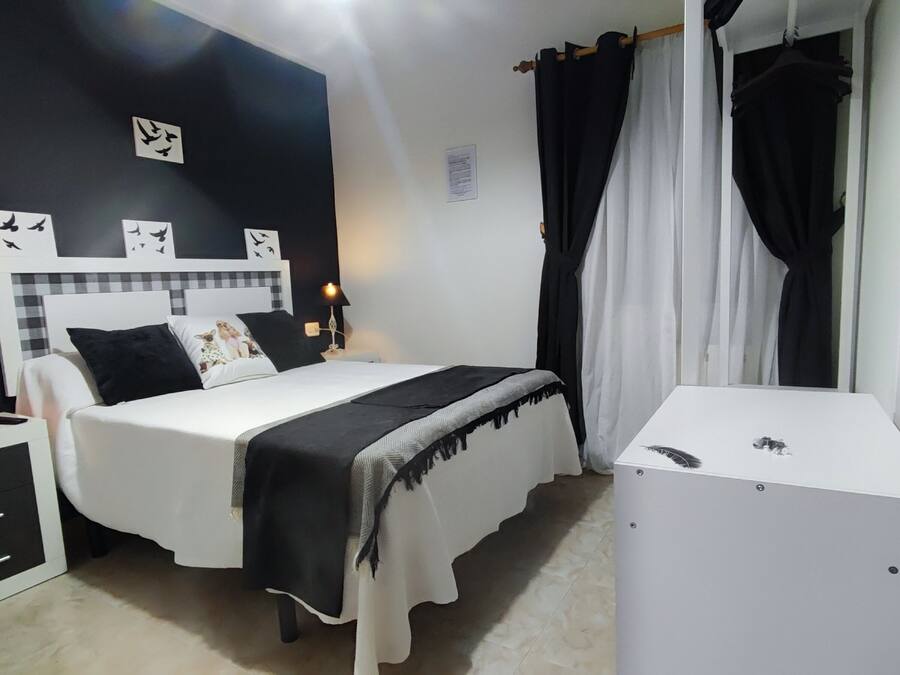 Un dormitorio con cama, mesitas de noche, escritorio y armario.