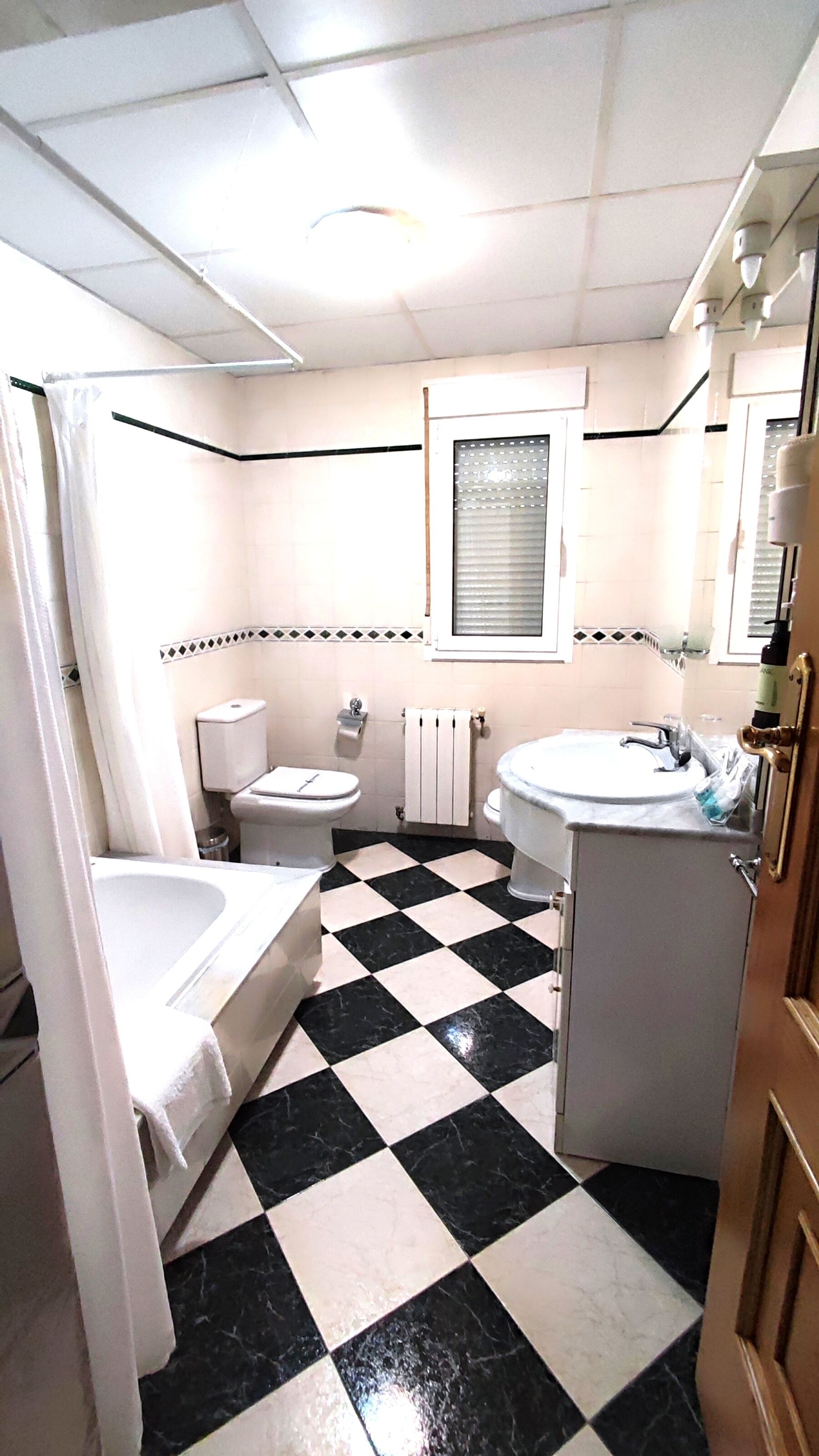 A bathroom with a checkered floor, a bathtub, a toilet, and a sink.