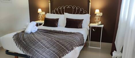 A neatly made bed with a patterned blanket, two bedside tables with lamps, and a headboard with a decorative design.
