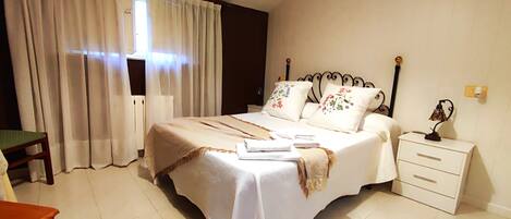 A neatly arranged bedroom with a bed, bedside tables, and a chair.
