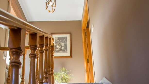 A staircase with granite steps and wooden balusters, leading to a room with a framed picture on the wall. - Casa Brais (Barreiros)