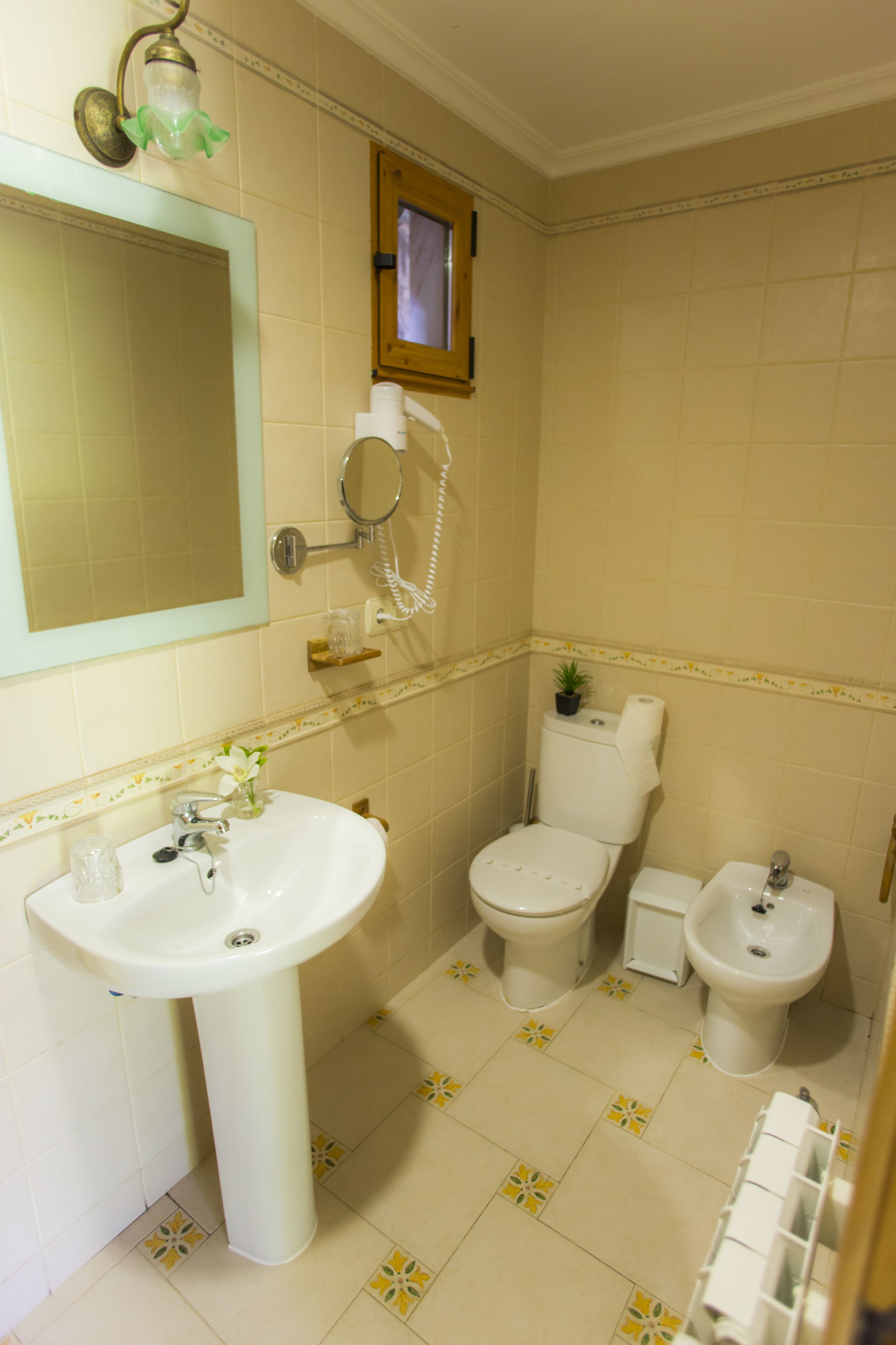 A bathroom with a sink, toilet, bidet, and a mirror.