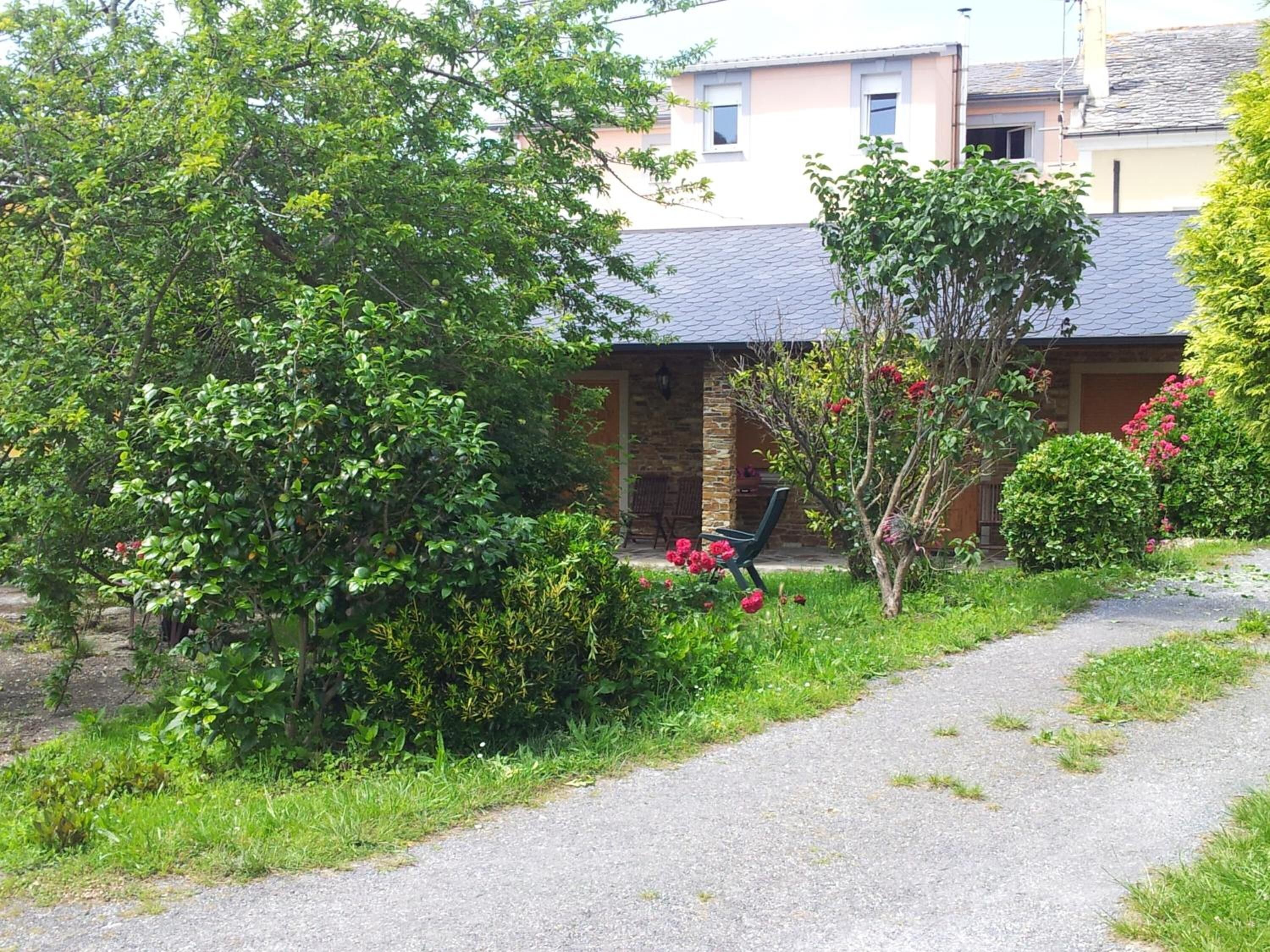 A pathway leading to a building with a stone facade and a covered porch.