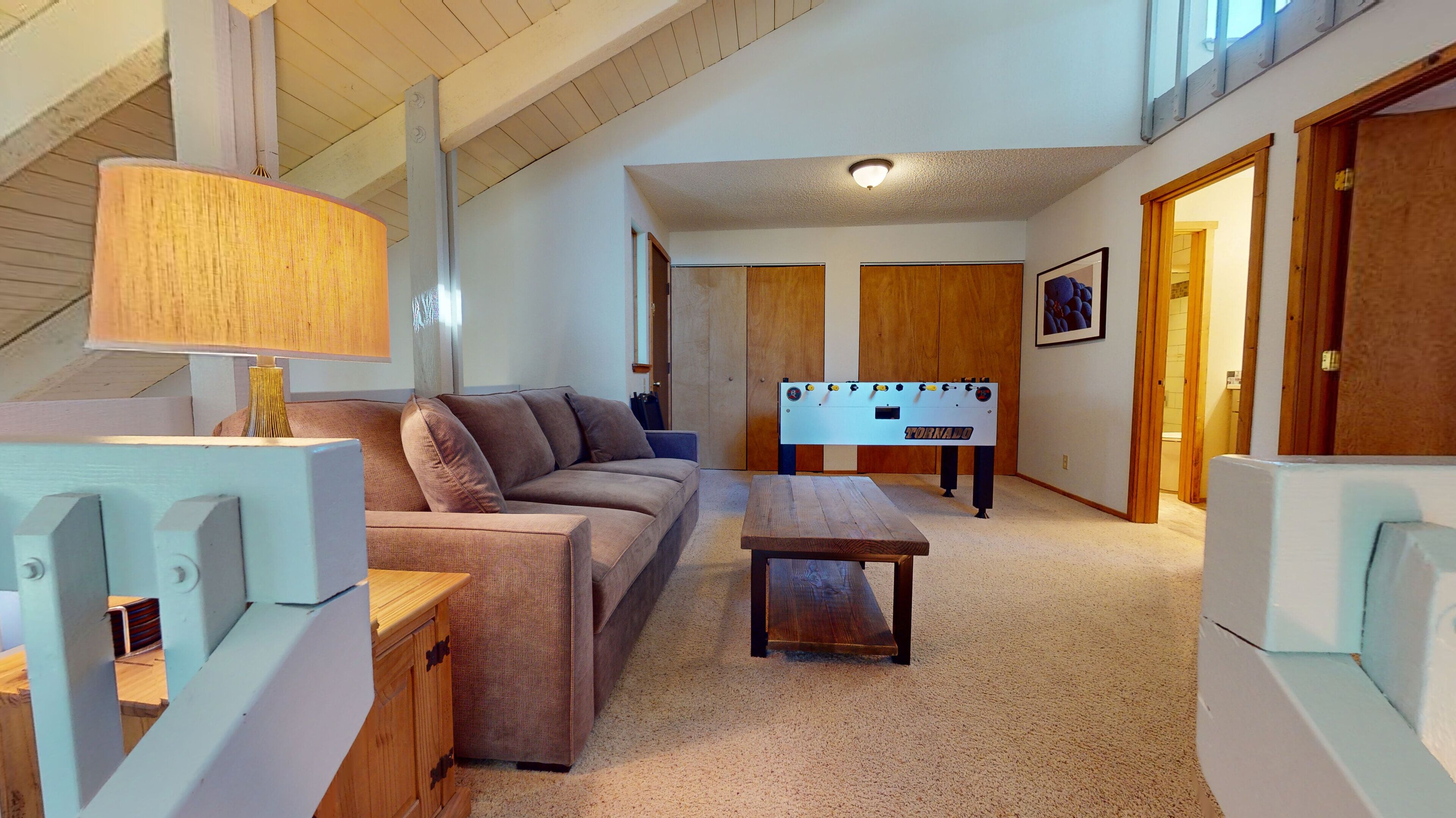 A cozy room with a sofa, a wooden table, and a foosball table.