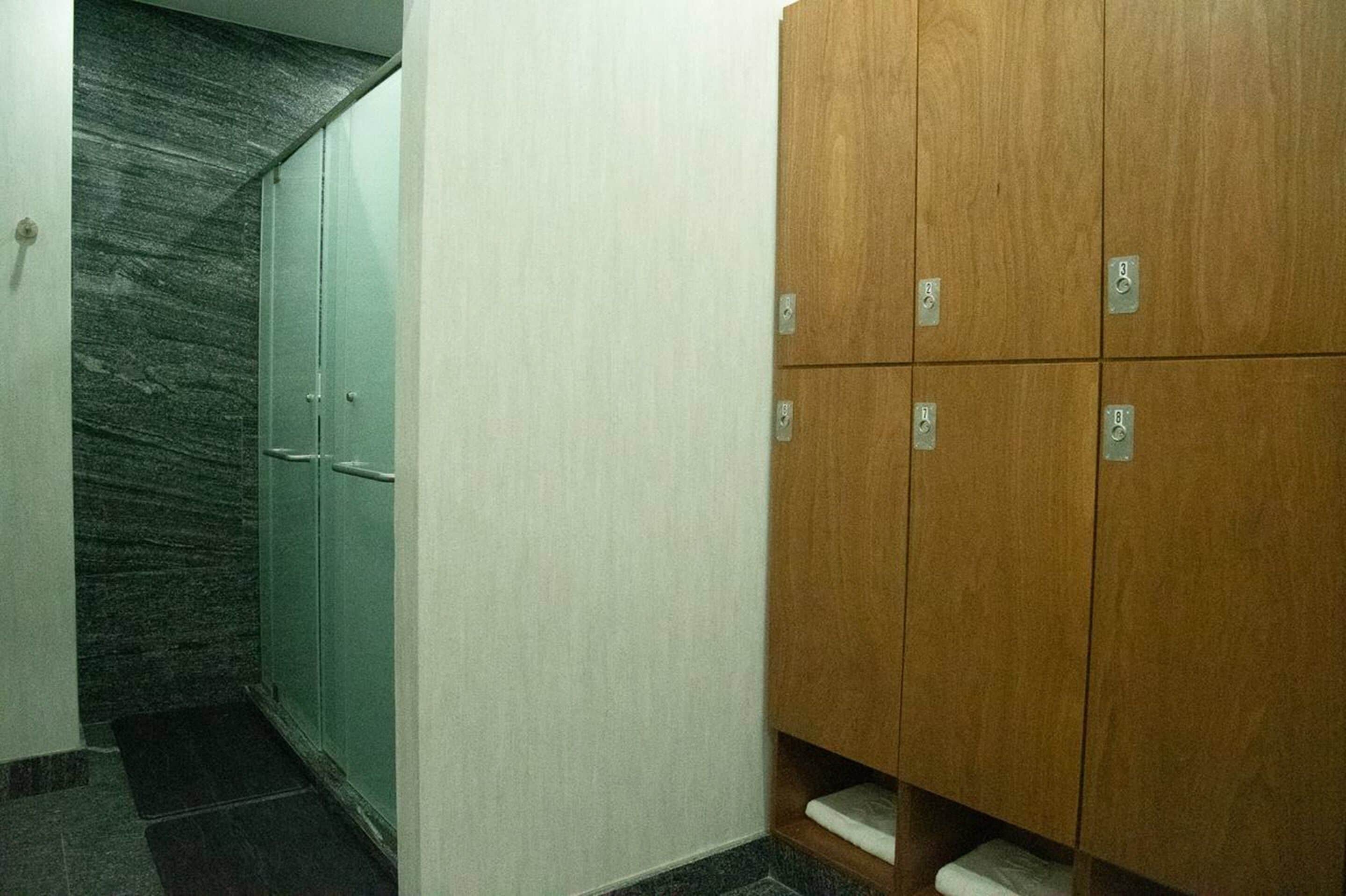 Un pasillo con pared de mármol, un mueble de madera con varios compartimentos y piso de baldosas.