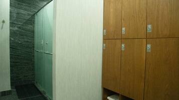 Un pasillo con pared de mármol, un mueble de madera con varios compartimentos y piso de baldosas.