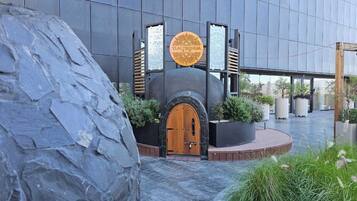 Stunning entrance with a circular emblem above the door, flanked by lush greenery and stone accents.