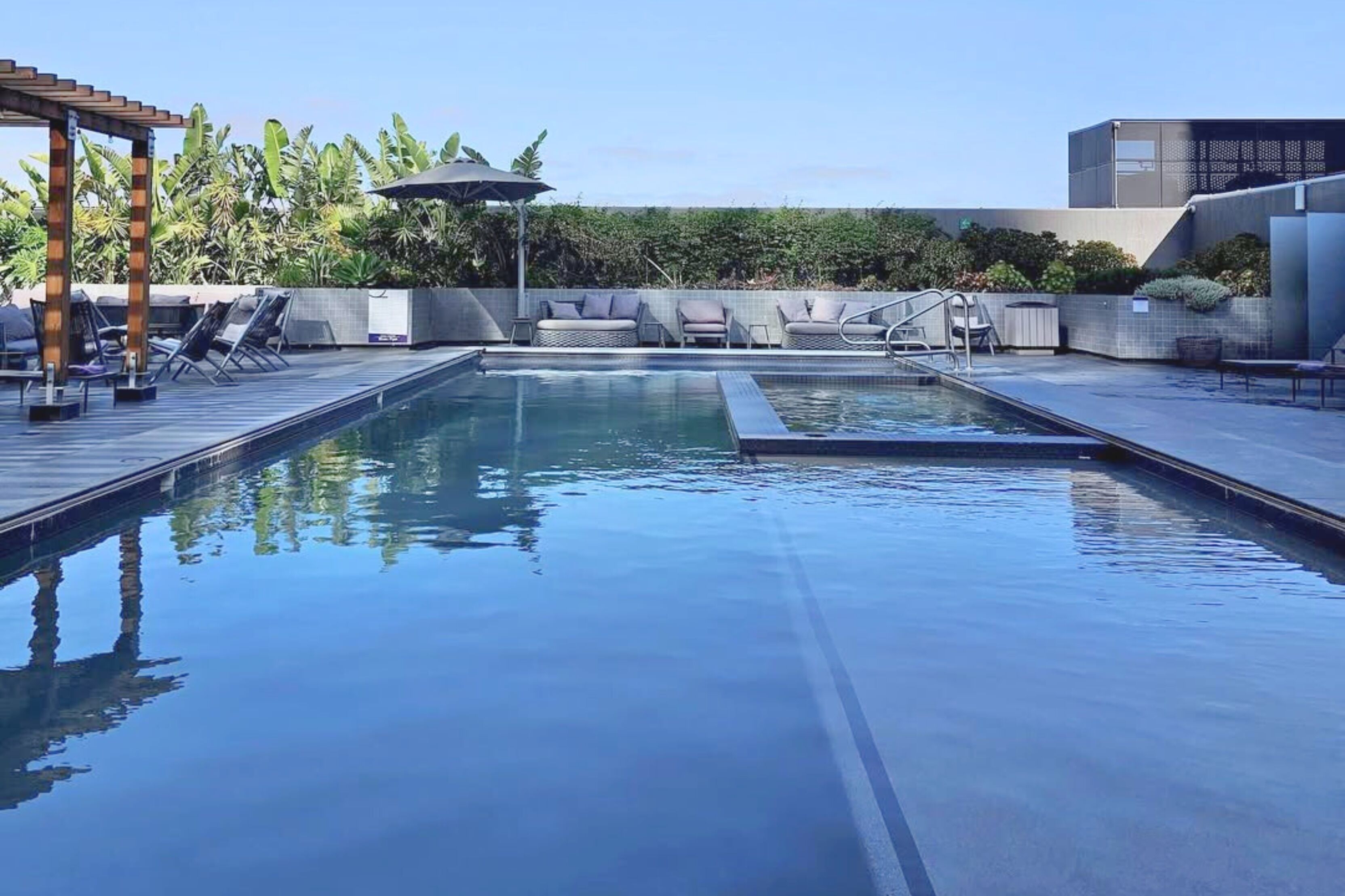 A modern outdoor pool area with lounge chairs and a pergola.