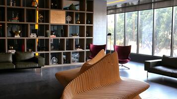 A modern living room with a unique textured sofa, a dark leather couch, and a minimalist shelving unit with various decorative items.