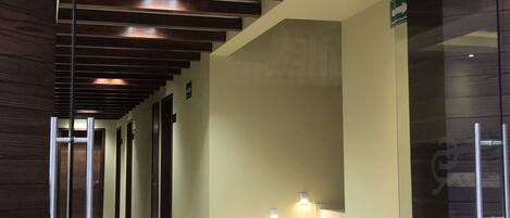 Un pasillo moderno con suelo estampado, pared de vidrio a la derecha y techo de madera.