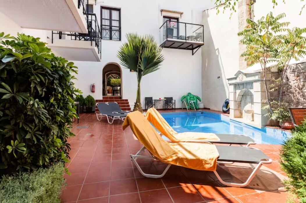 A poolside area with lounge chairs, a palm tree, and a small garden.