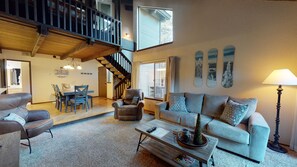 Relax in this spacious living area with a high ceiling, featuring a sofa set, coffee table, and dining area.