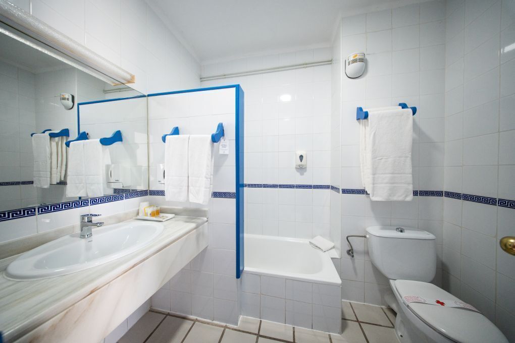 Une salle de bain avec un lavabo, un miroir et des toilettes.