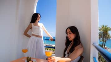 Dos personas en una mesa con bebidas y fruta, con vistas a la costa.