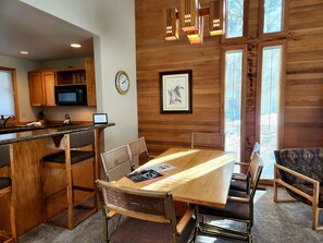 Un intérieur en bois avec une table à manger, des chaises, une horloge et un tableau encadré au mur.