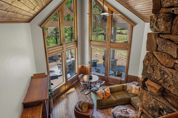 A cozy room with a stone wall, large windows, a wooden ceiling, and a green sofa. - Caldera Springs Lodge with Access to Exclusive Golf (Bend)