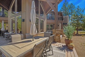 Una terraza de madera con mobiliario exterior, zona de barbacoa y un muro de piedra.