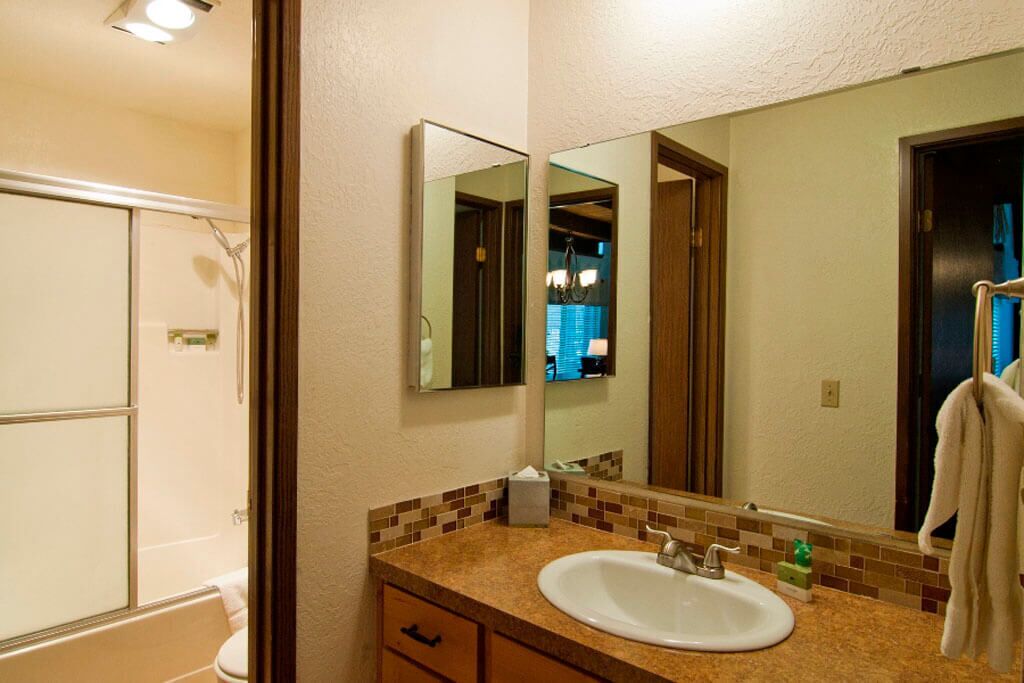 A bathroom with a sink, mirror, and shower.