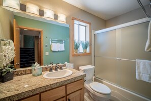 A bathroom with a granite countertop, a white sink, a toilet, and a glass shower enclosure. - Quiet Sunriver Retreat with Access to The Cove (Sunriver)