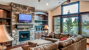Una sala de estar acogedora con chimenea de piedra, un televisor de pantalla plana grande y un sofá confortable.