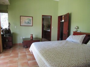 A bedroom with a bed, a dresser, a nightstand, a vase, and a painting on the wall. - Leave the Cold behind, Winter in the Safe Quiet Paradise of Costa Rica (N/A)