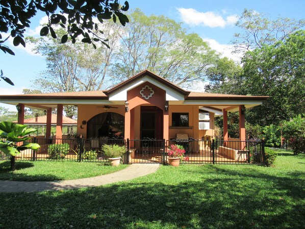 A house with a covered porch, a barbecue area, and a well-maintained lawn. - Leave the Cold behind, Winter in the Safe Quiet Paradise of Costa Rica (N/A)