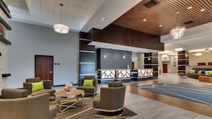 Un hall amplio con mobiliario moderno, una zona de recepción y un techo de madera.