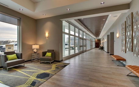 A spacious hallway with modern seating, large windows, and a patterned rug.