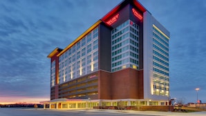 Un hotel de varios pisos con un llamativo letrero 'DRURY', ventanas amplias y un garaje para estacionar.