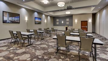A conference room with tables and chairs, a projector, and a screen.