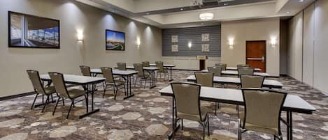 A conference room with tables and chairs, a projector, and a screen.
