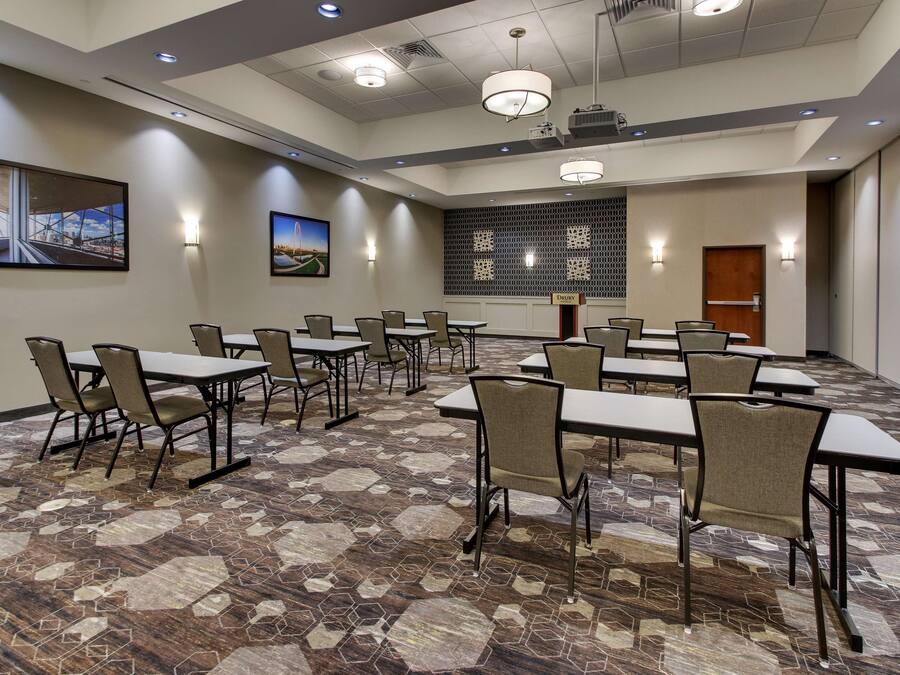A conference room with tables and chairs, a projector, and a screen.