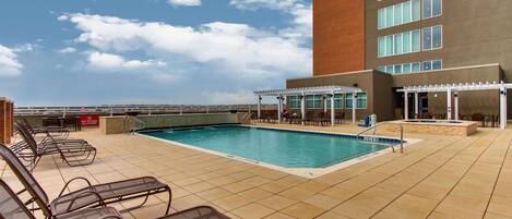 A rooftop pool area with lounge chairs and a covered seating area.