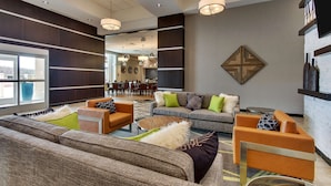 Un vestíbulo moderno con una variedad de zonas de estar, incluyendo sofás y sillones, y un comedor al fondo.
