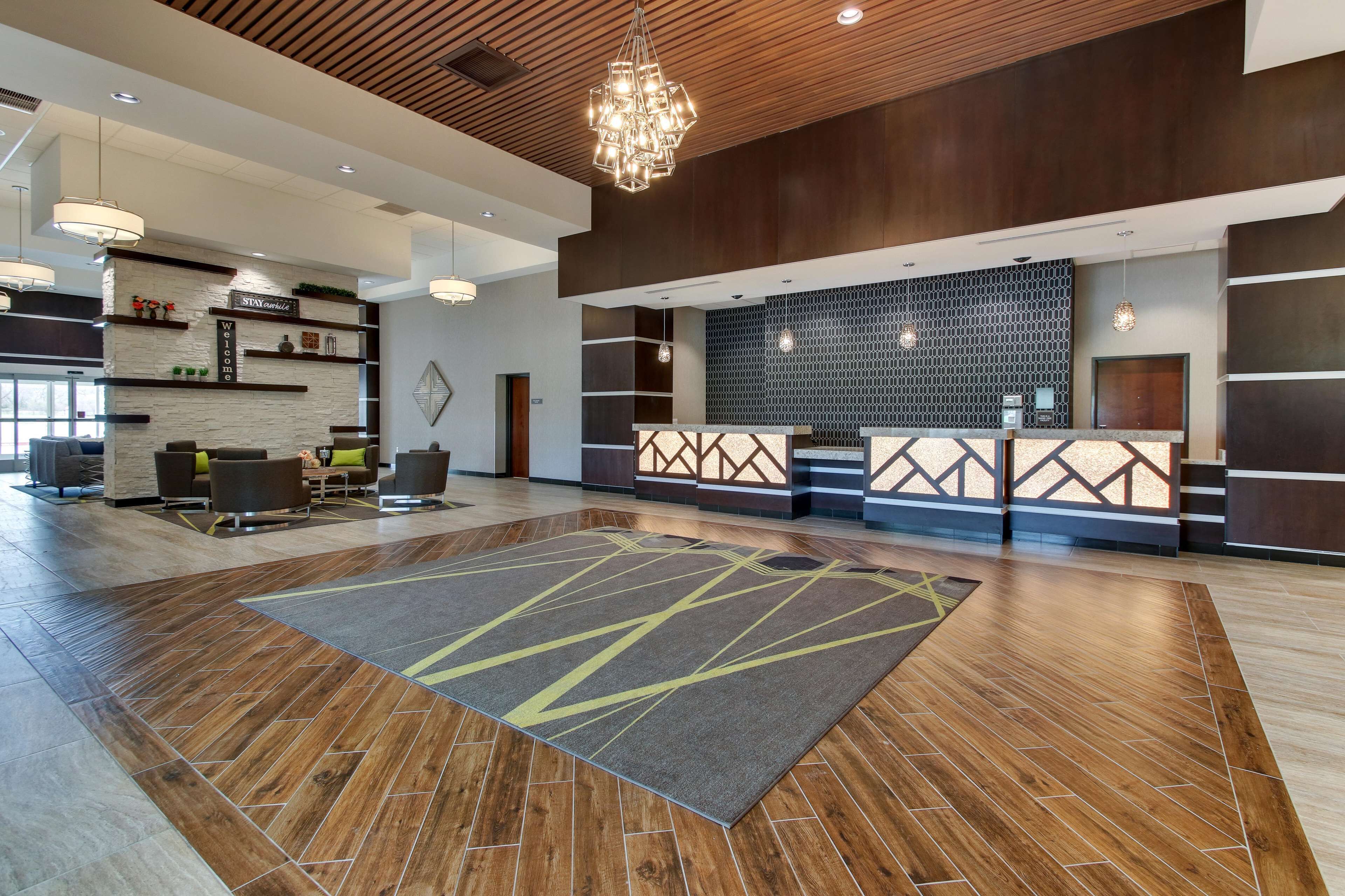 Un amplio vestíbulo con piso de madera, una mesa de recepción y un área de estar con sillas y un sofá.