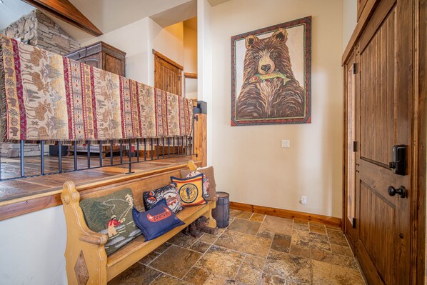 A wooden bench with decorative pillows, a stone fireplace, and a bear-themed painting on the wall.
