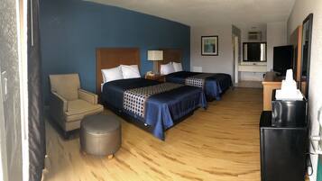 Habitación de hotel con dos camas, un escritorio, una silla, un cesto de basura y un televisor.