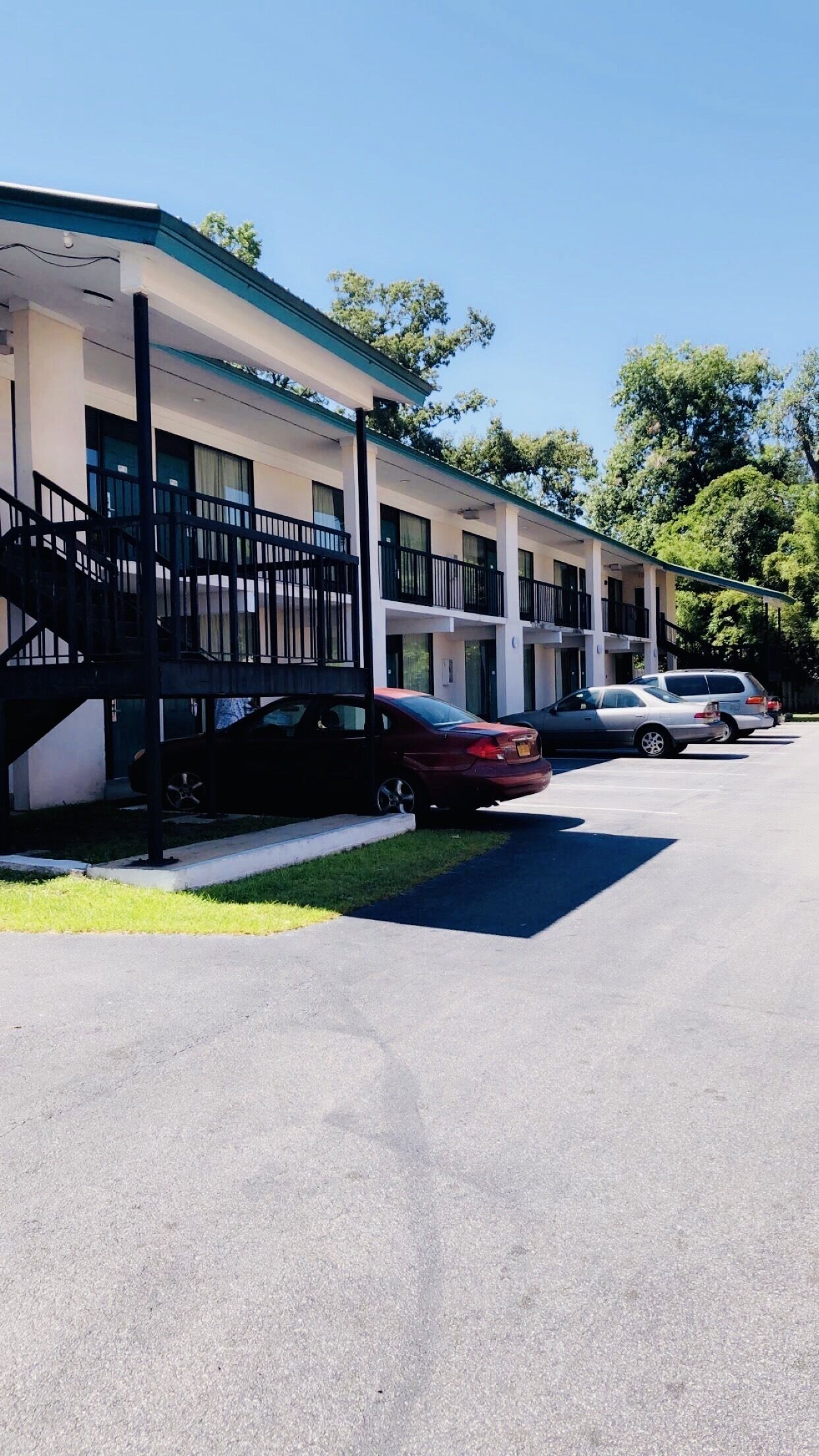 A motel with a covered parking area and a staircase leading to the entrance.