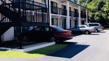 A motel with a covered parking area and a staircase leading to the entrance.