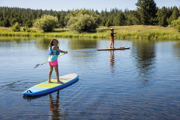 Two people paddleboarding on a calm lake with a forest in the background. - Caldera Cabin with Access to Foresthouse (Bend)