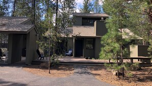 A two-story building with a covered patio area, surrounded by trees. - Cozy Family Cabin with Access to Exclusive Golf (Sunriver)