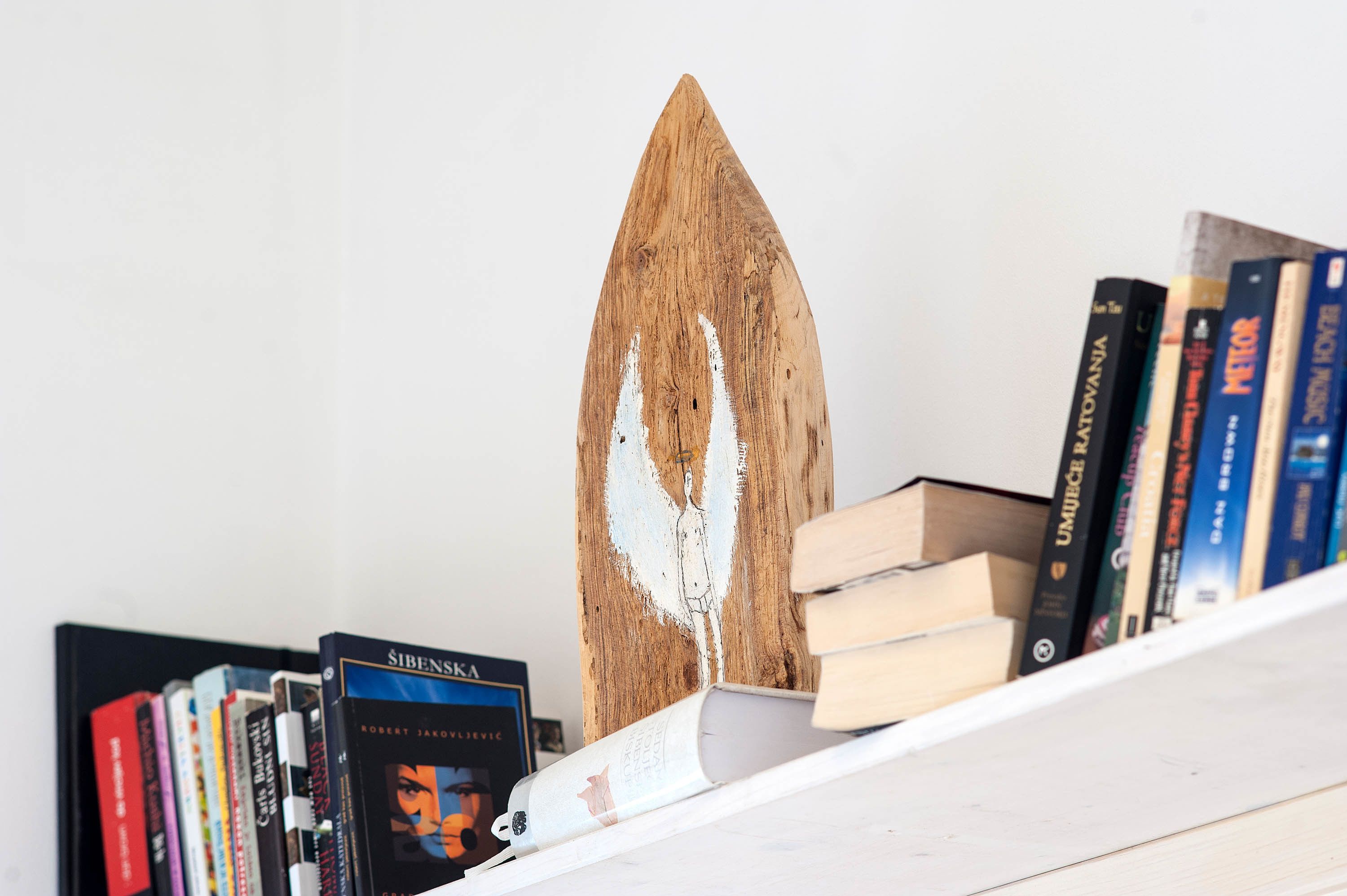 Una estantería con libros y un objeto de madera.