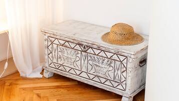Un cofre de madera blanca con un aspecto envejecido, adornado con patrones geométricos y un sombrero de paja encima.