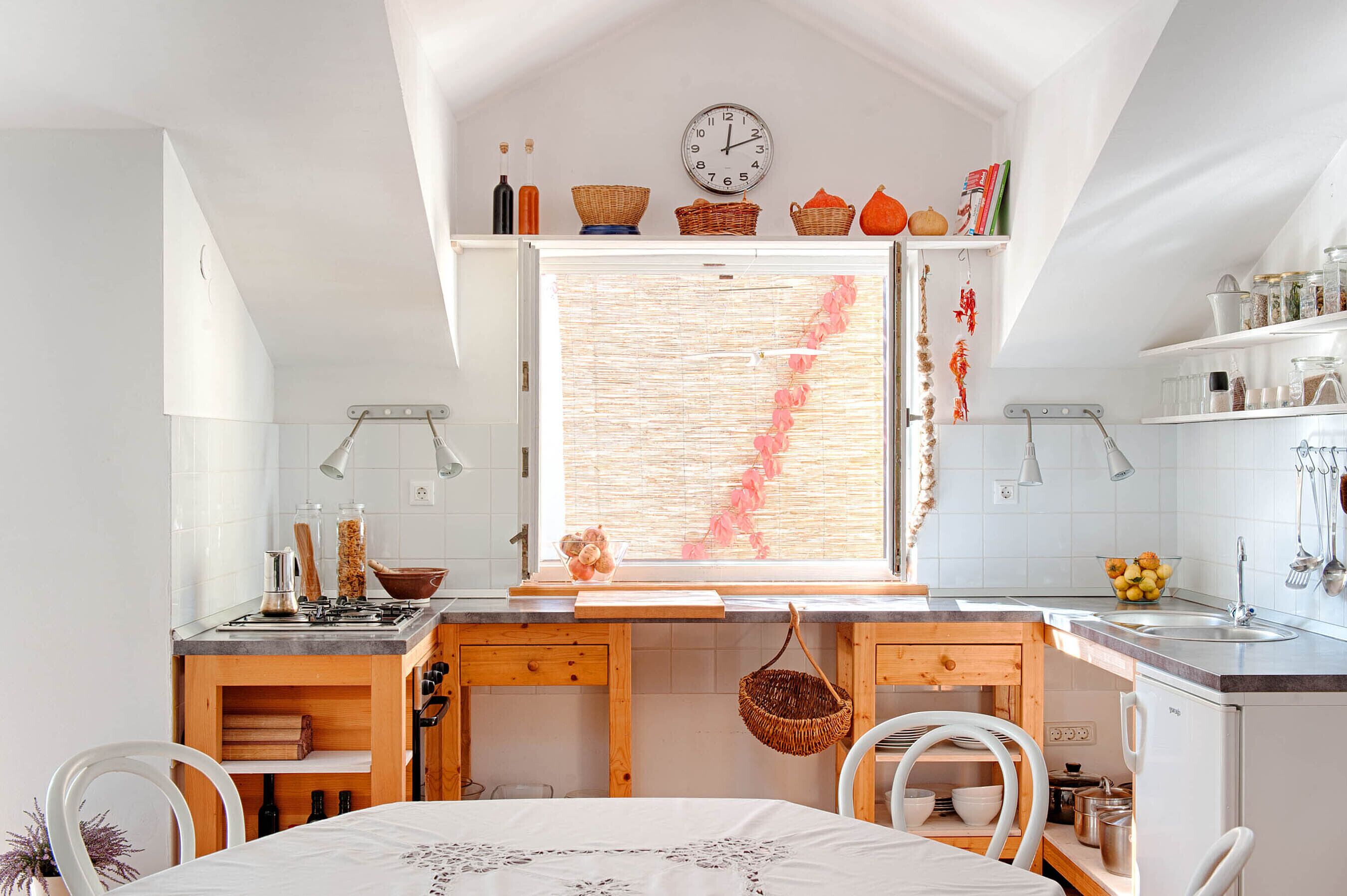 A compact kitchen with a central island, a dining area with a table and chairs, and a window with a view.