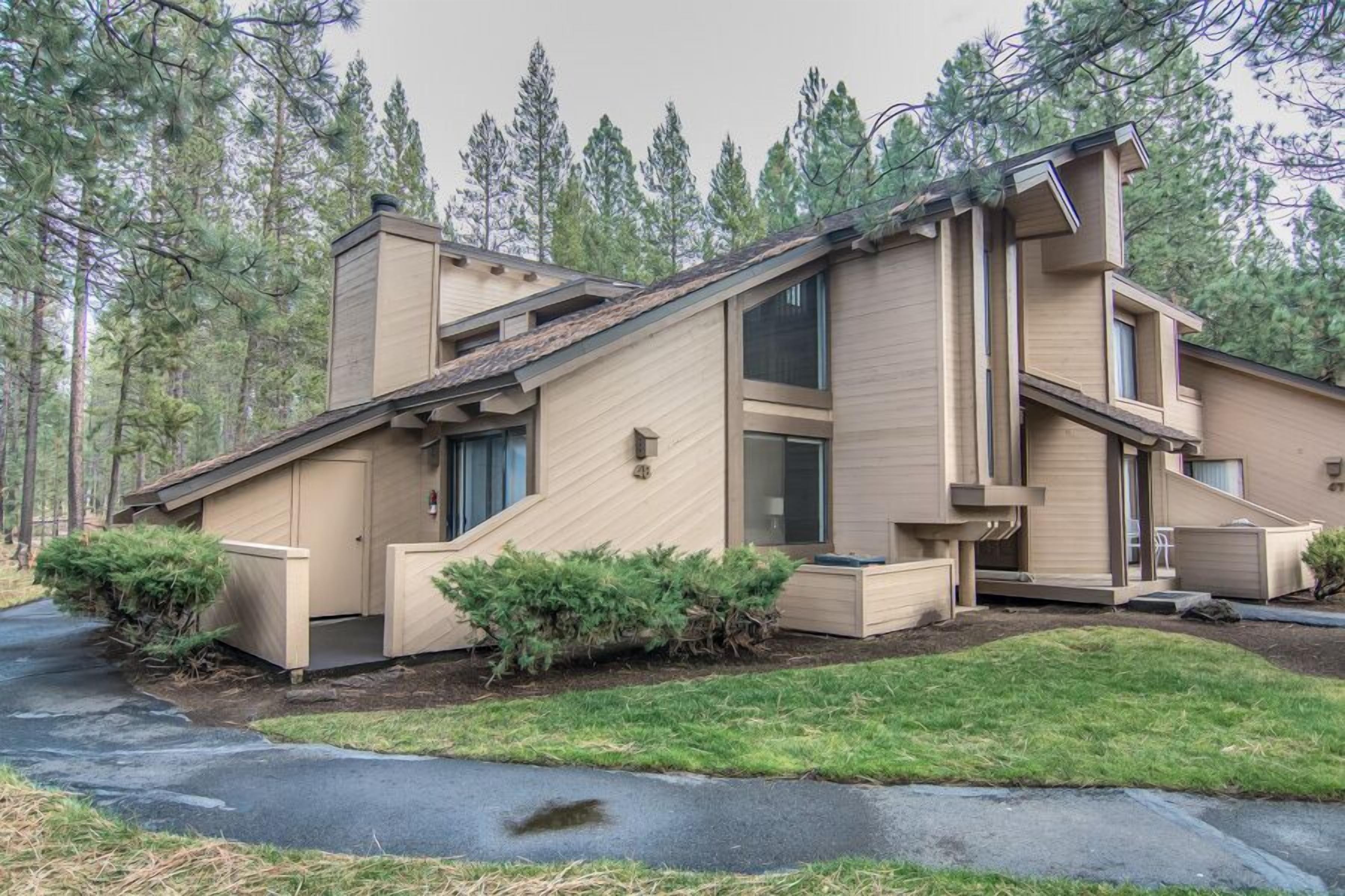 A modern two-story house with a sloped roof, large windows, and a well-maintained lawn.