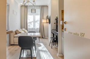 Una sala de estar moderna con un sofá, una mesa de comedor, sillas, un piano y una lámpara.